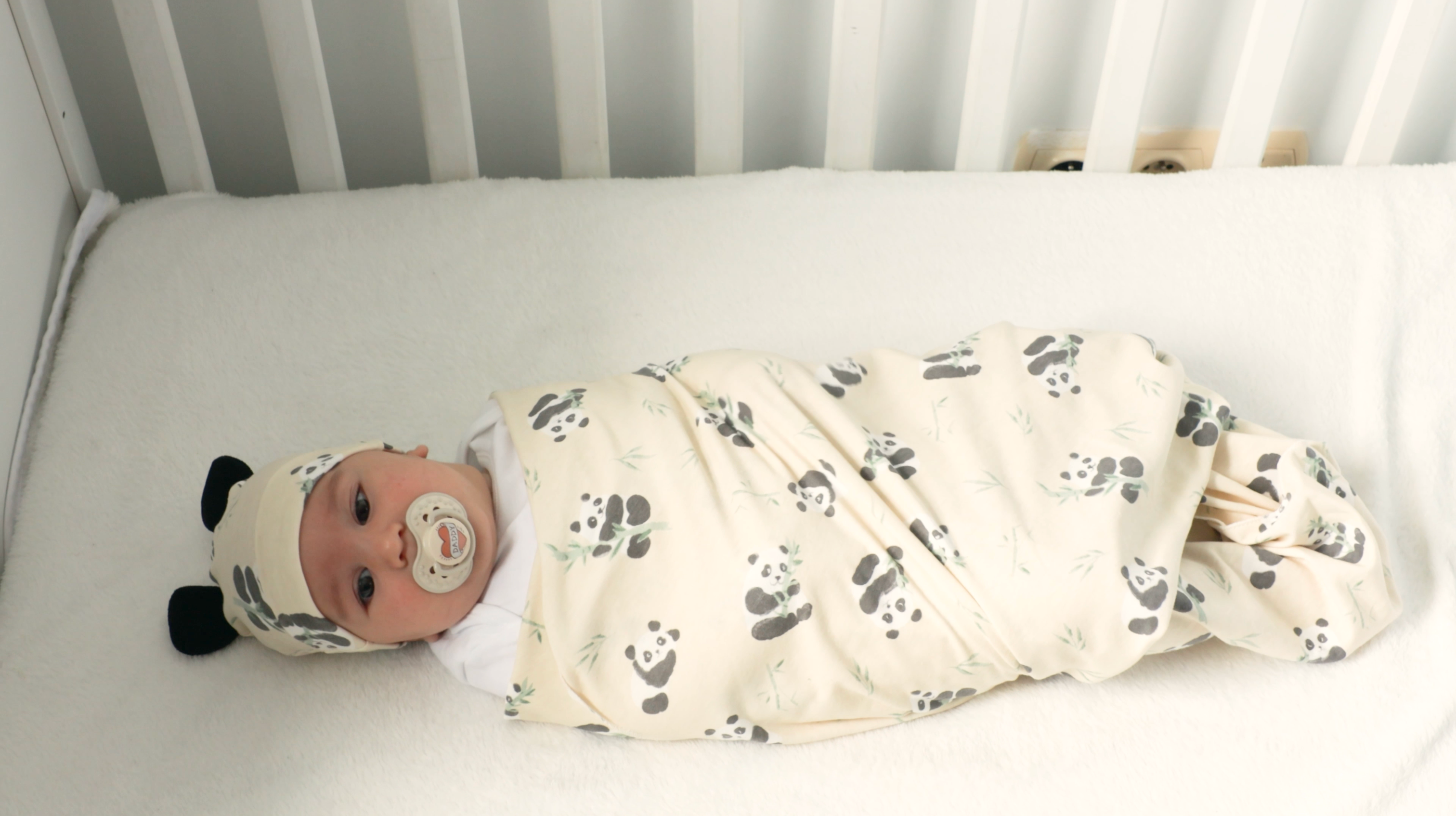 Load video: Video showing mother swaddling her baby in our swaddling blanket and putting on the panda hat.